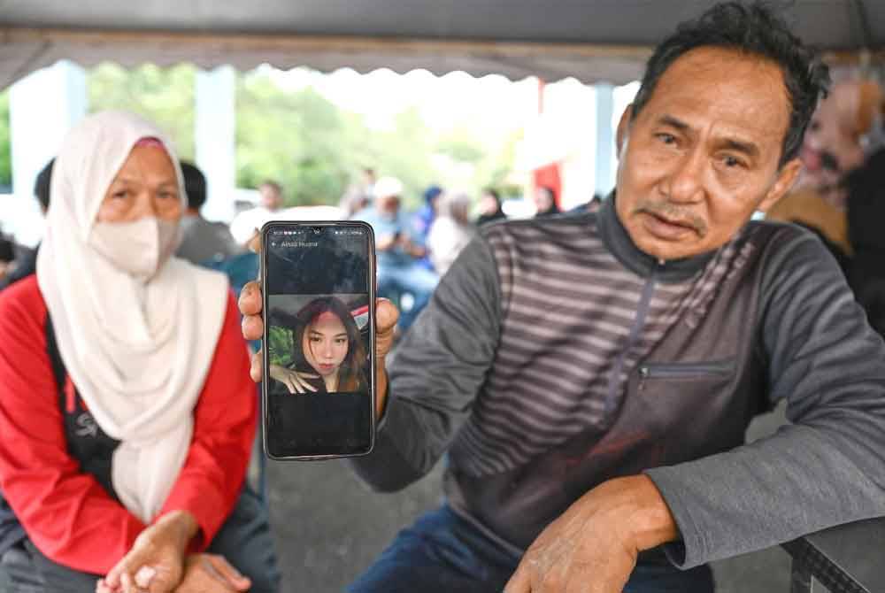 Muhamad Husaini bersama Haziyah menunjukkan gambar Aina Husna yang masih hilang selepas bot dinaiki dilanggar sebuah tongkang dalam kejadian pada pagi Ahad.