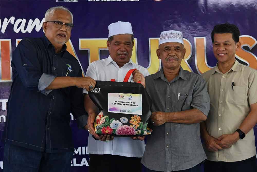 Mohamad (dua, kiri) menyampaikan bantuan bakul makanan kepada penerima Ghani Mat Piah (dua, kanan) pada Program Libat Urus KPKM bersama pemimpin Pertubuhan Peladang Kawasan Gua Musang pada Isnin. Foto Bernama