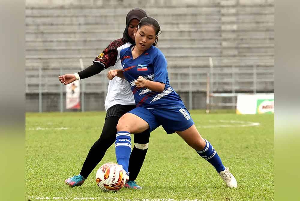 Tonggak Sabah Adlin Bandi mengasak pemain Pahang pada aksi pembukaan Kumpulan A saingan bola sepak wanita Sukma Sarawak 2024 pada Rabu.