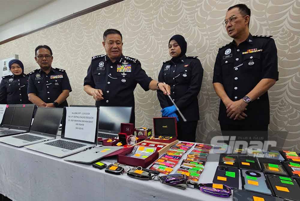 Azizi (tengah) menunjukkan barangan yang dirampas dalam serbuan di dua rumah yang dijadikan pusat panggilan sindiket tawaran pekerjaan tidak wujud dalam talian di Taiping.