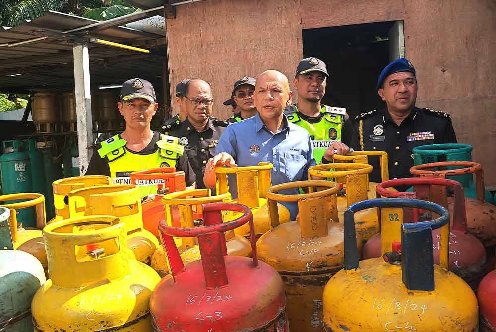 Armizan (tengah) melakukan tinjauan di premis yang diserbu KPDN di Lukut pada Jumaat.