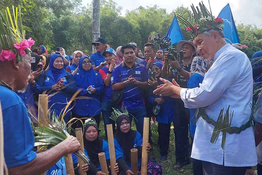 Ahmad Zahid (kanan) terhibur dnegan persembahan masyarakat Orang Asli ketika turun berkempen di Pos Pulat, Gua Musang pada Jumaat.