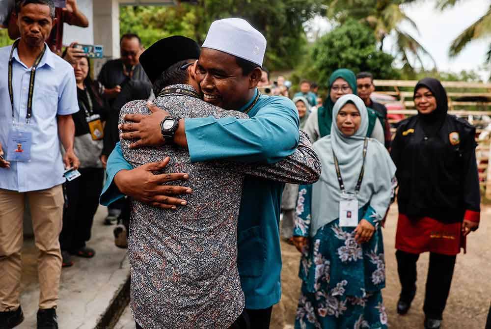 Mohd Azmawi (kiri) dan Mohd Rizwadi berpelukan selepas mengundi pada PRK Nenggiri di Pusat Mengundi Tabika Sri Bakawali, Bertam Lama pada Sabtu. Foto Bernama