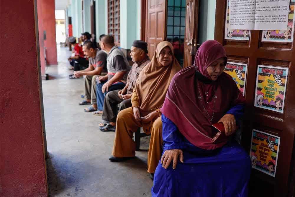 Orang ramai beratur menunggu giliran bagi menunaikan tanggungjawab mengundi pada PRK DUN Nenggiri di Pusat Mengundi Sekolah Kebangsaan Jeram Tekoh hari ini. Foto Bernama