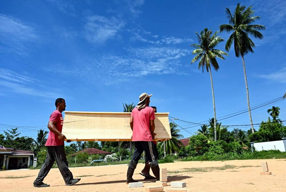 Maridwan (kiri) mengangkat keranda yang telah siap dipasang ketika tinjauan di Kampung Padang Kemunting, Batu Rakit. Foto Bernama