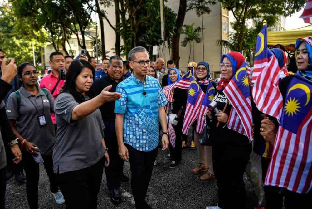 Fahmi (tengah) ketika hadir pada Program Edaran Jalur Gemilang sempena Bulan Kebangsaan di Pasar Pagi PPR Kerinchi pada Ahad. Foto Bernama