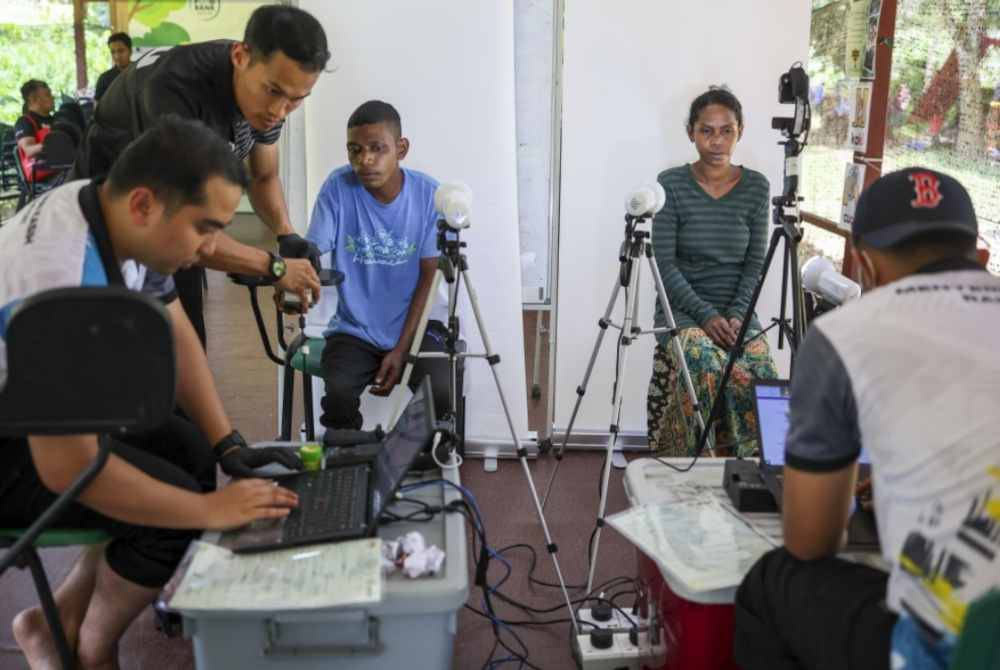 Petugas JPN membantu Orang Asli melakukan proses permohonan kad pengenalan. Foto Bernama