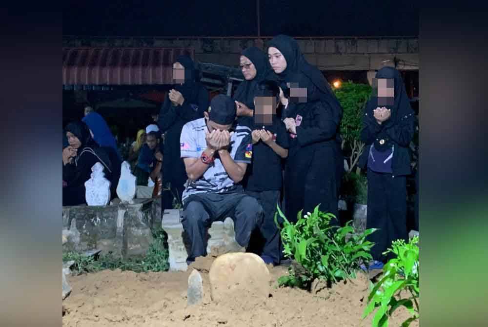 Yusof Mokhtar, 35, (kiri) ditemani ahli keluarga mengaminkan doa selepas selesai pengebumian jenazah isterinya, Istiqomah Ahmad, 33, yang dikebumikan di Tanah Perkuburan Islam Pengkalan Mengelong malam tadi.