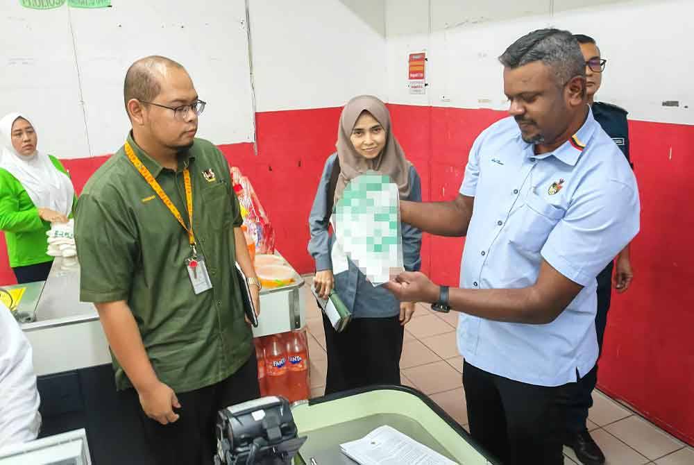 Arul (kanan) ketika melakukan pemantauan penggunaan beg plastik di sebuah pasar raya pada Selasa.