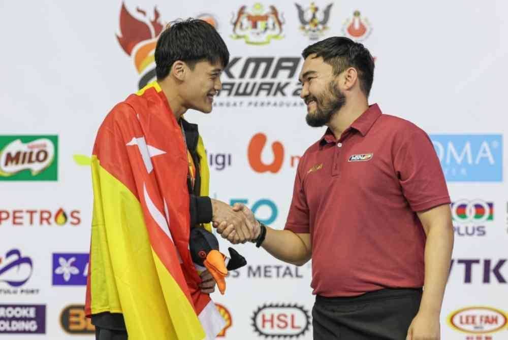 Tengku Amir (kanan) mengucapkan tahniah kepada Andrew yang meraih emas dalam acara 50m gaya kuak dada lelaki Sukma Sarawak 2024 di Pusat Akuatik Pandelela Rinong.