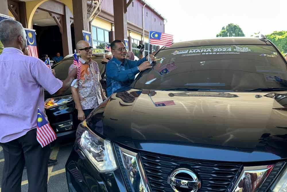 Mohd Faizul (tiga dari kiri) melekatkan Jalur Gemilang ke kenderaan rasmi Kada.