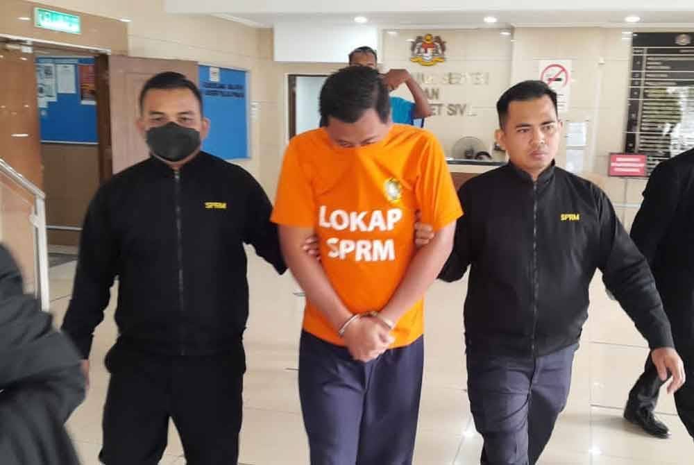 Anggota SPRM mengiringi inspektor polis yang direman kerana dipercayai menerima rasuah bagi menyelesaikan kes judi laga ayam.