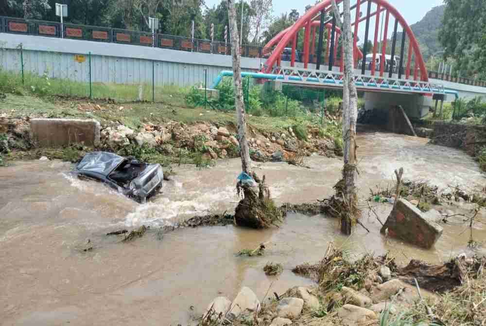 Kereta jenis Almera dihanyutkan ke dalam sungai akibat arus deras kepala air di kawasan parkir SkyCab di Oriental Village, Langkawi pada Jumaat. - Foto: PDRM