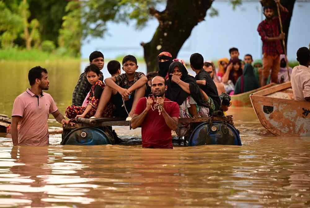 Orang ramai mengharungi air banjir di Feni selepas hujan lebat membanjiri kawasan rendah di Bangladesh - Foto: AFP