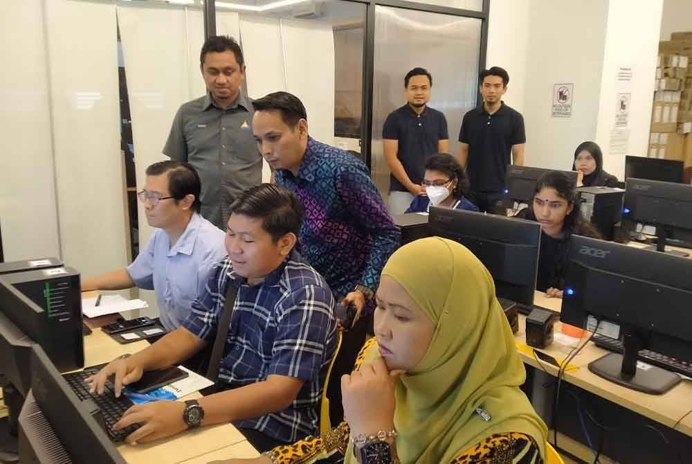 Mohd Azlan (berdiri, kanan) melihat hasil kerja peserta selepas menyempurnakan Majlis Pelancaran MCMC Microsoft AI Teach Peringkat Negeri Perak di Hab Inovasi dan Multimedia, Bandar Meru Raya di sini pada Sabtu.