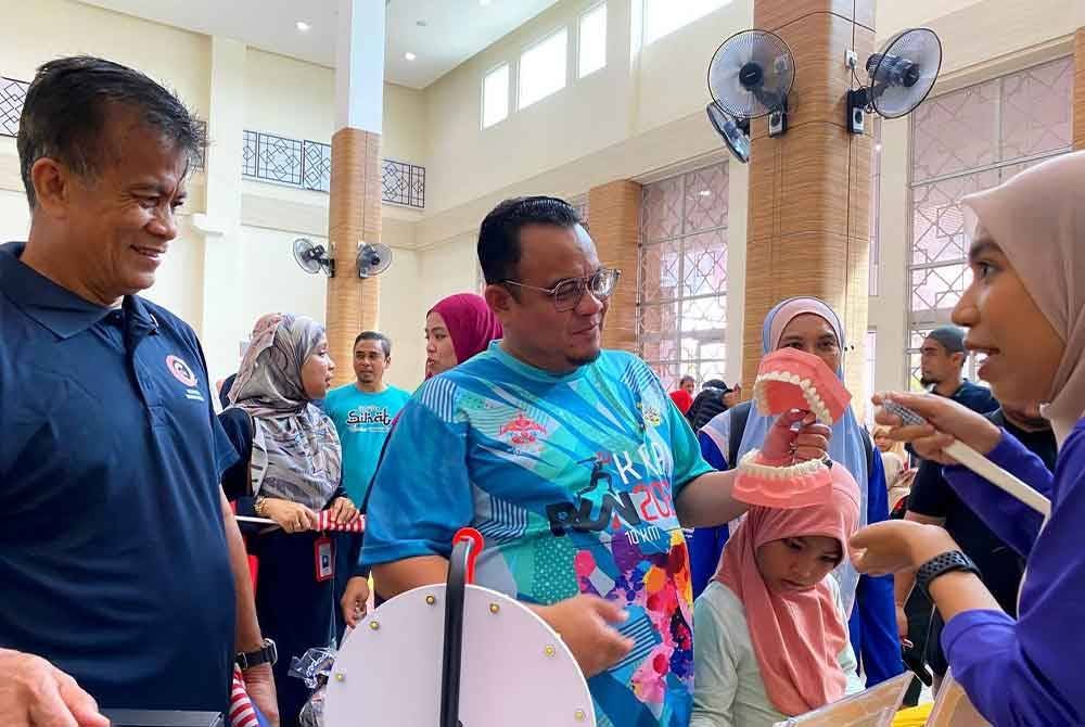 Dr Zaini (kiri) dan Helmi (dua dari kiri) mendengar penerangan semasa melakukan lawatan ke pameran Karnival Promosi Kesihatan, Hari Terbuka Hospital Kluster Kelantan Barat dan Program Kelantan Sihat Peringkat Hospital Tanah Merah pada Sabtu.