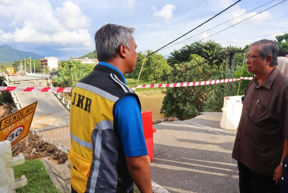 Muhammad Nizar (kanan) semasa meninjau keadaan runtuhan Jambatan Lama Sungai Slim di Jalan Slim River-Behrang Ulu pada Sabtu.