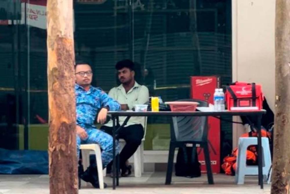 Anak mangsa tanah jerlus, Surya (duduk, kanan) kelihatan sugul ketika berada di lokasi kejadian tanah jerlus di Masjid India.