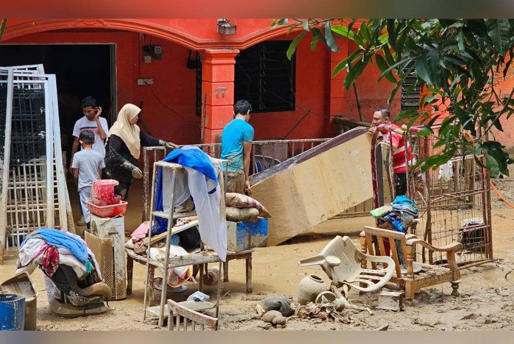 Penduduk melakukan pembersihan selepas rumah mereka dipenuhi lumpur di Kampung Pasir, Ulu Slim dekat Slim Village pada Ahad.