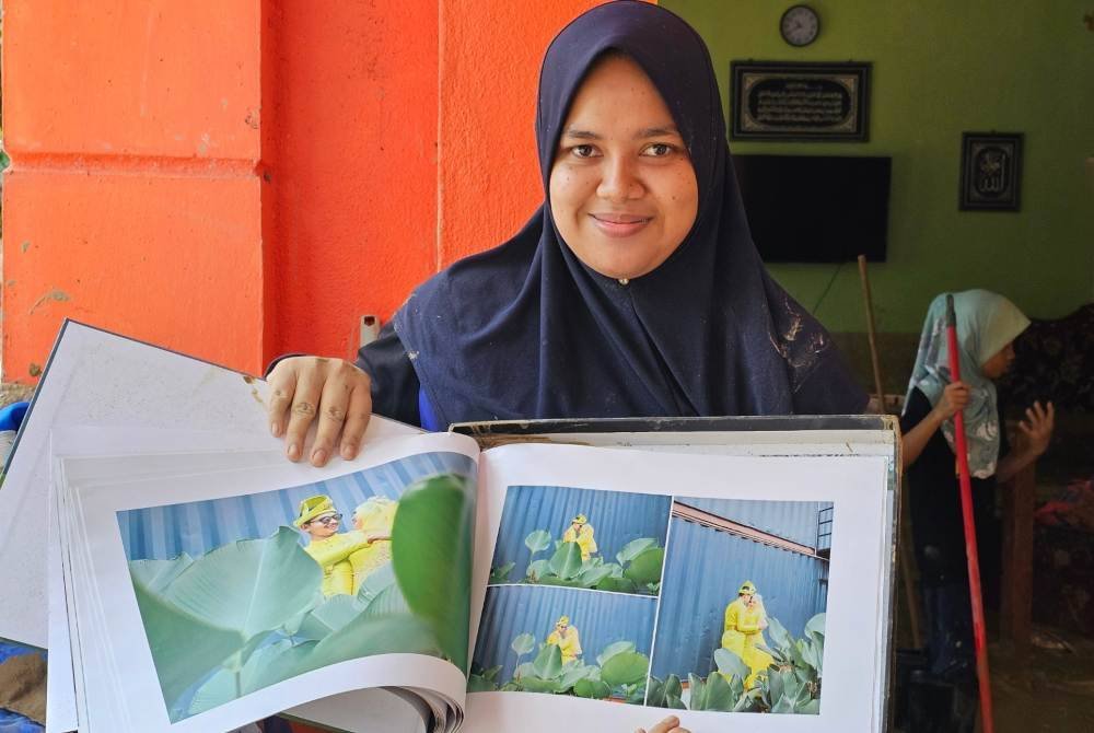 Nur Ayu Fazira menunjukkan gambar perkahwinannya yang masih elok walaupun kediaman keluarganya terjejas banjir dalam insiden kepala air di Kampung Pasir, Kampung Ulu Slim di Tanjung Malim.