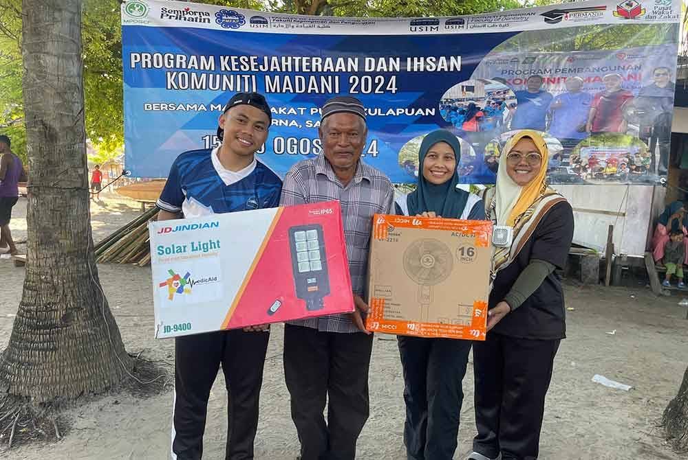 Wakil USIM menyerahkan lampu solar dan kipas kepada Ketua Kampung Pulau Kulapuan, Alawi Malik (dua dari kiri) di Semporna, Sabah baru-baru ini.