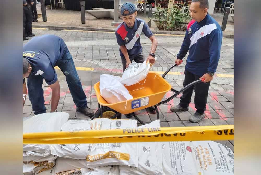 Petugas DBKL melaksanakan kerja-kerja mengangkat beg pasir untuk diletakkan di keliling tanah jerlus di Jalan Masjid India, pada Isnin.