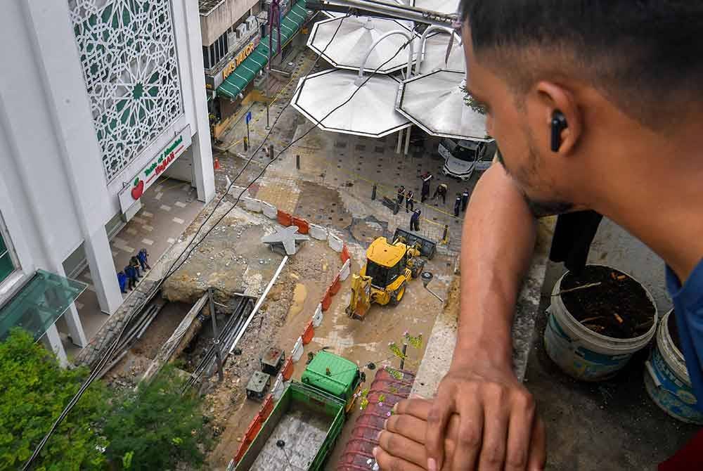 Penduduk sekitar melihat keadaan terkini di sekitar operasi pencarian warga India yang menjadi mangsa insiden tanah jerlus di Jalan Masjid India pada Isnin. Foto Bernama