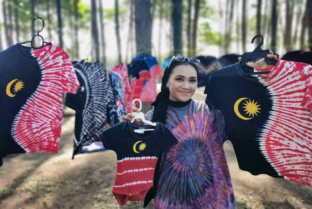 Pekerja House Of Tie Dye, Shasuhaida Abdullah menunjukkan antara baju T yang dijual di kawasan riadah dan rekreasi Pantai Sura, Dungun.