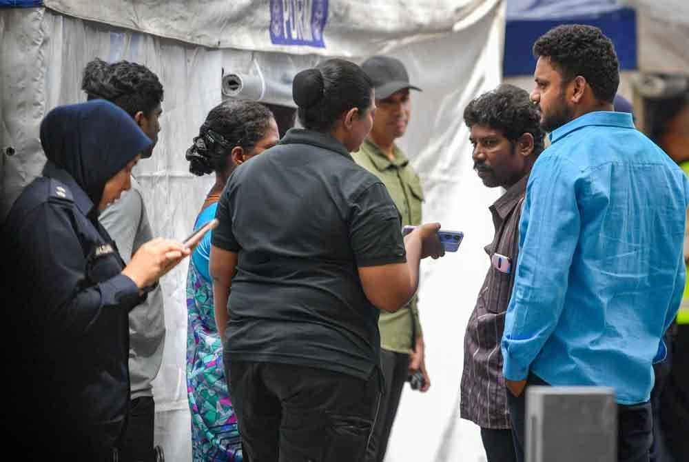 Suami kepada mangsa tanah mendap, warga India Mathavan (dua dari kanan), menunggu di lokasi kejadian untuk mendapatkan perkembangan terkini mengenai operasi mencari dan menyelamat (SAR) isterinya yang hilang dalam insiden tanah jerlus di Jalan Masjid India. Foto Bernama