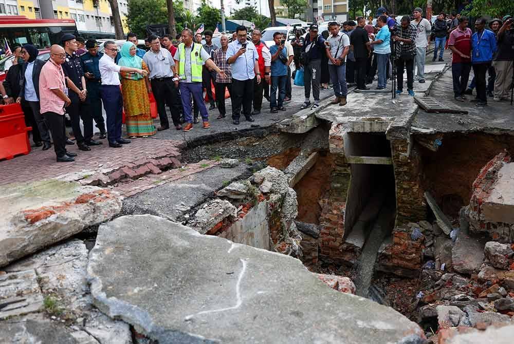 Fahmi dan Dr Zaliha Mustafa meninjau keadaan mendapan tanah yang berlaku di Jalan Pantai Permai, Kampung Kerinchi pada Rabu. Foto Bernama