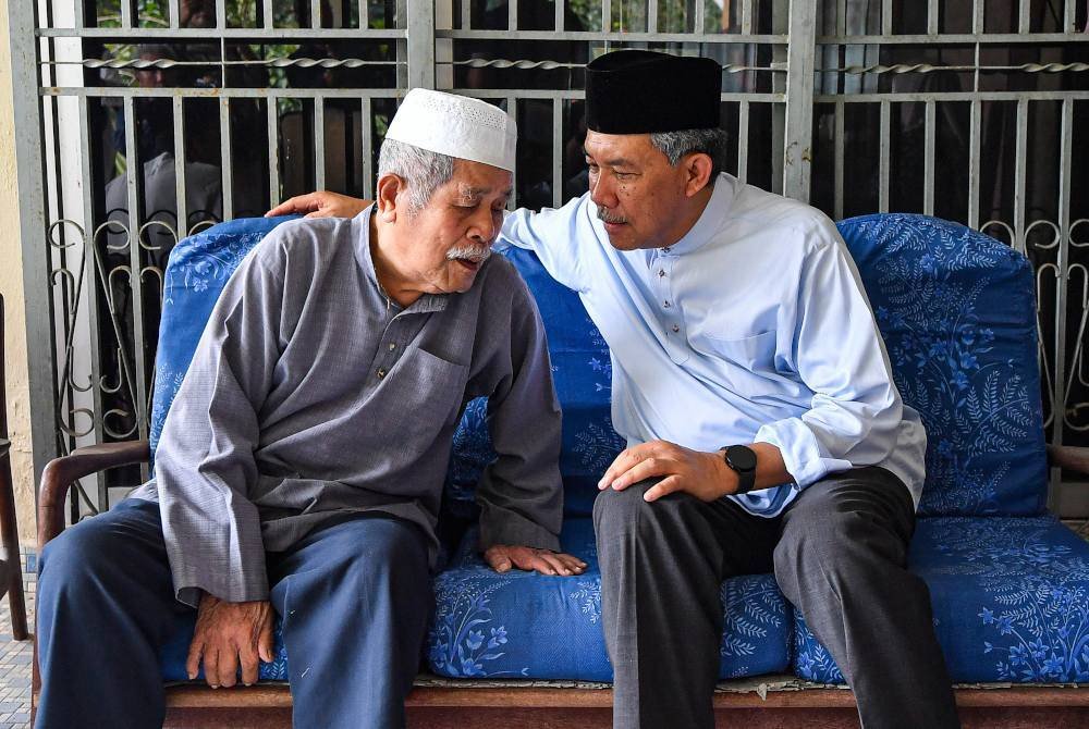 Mohamad (kanan) yang juga Ahli Parlimen Rembau menyantuni warga emas Abd Rahman Salam pada Ziarah Kasih Tokmat di Kampung Nerasau, pada Jumaat. Foto Bernama