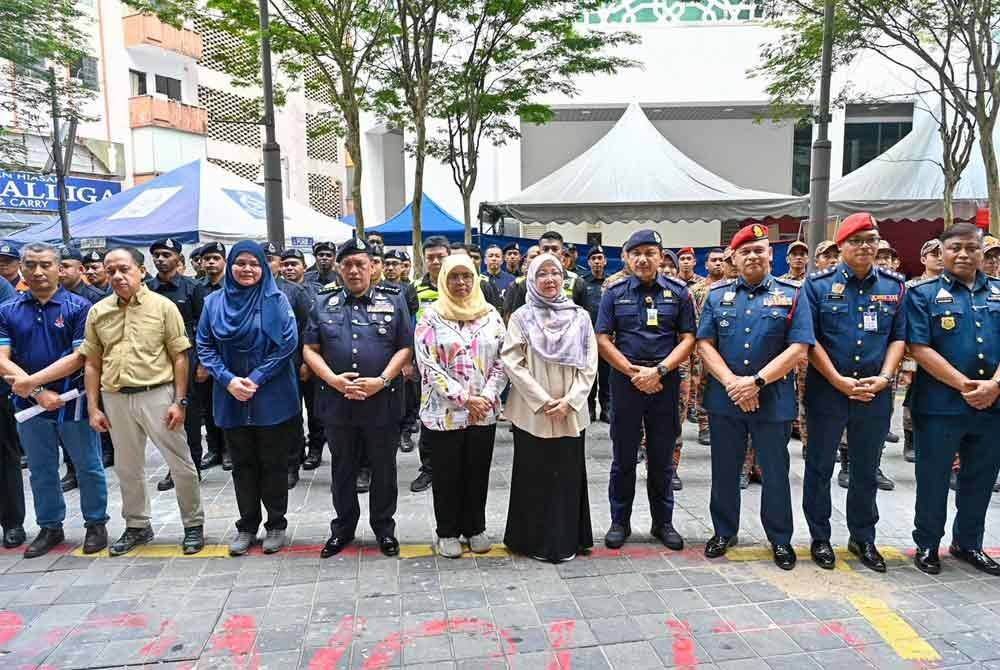 Zaliha (lima kanan) bergambar bersama pasukan penyelamat yang terlibat dalam operasi SAR mangsa tanah jerlus di Jalan Masjid India, Kuala Lumpur pada Sabtu.