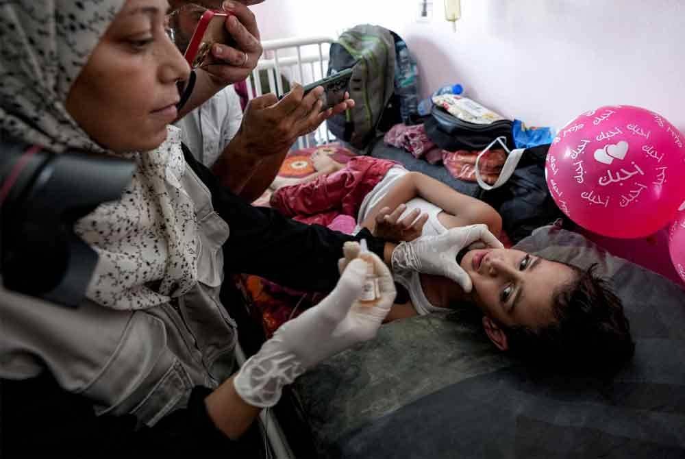 Seorang pekerja kesihatan memberi vaksin polio kepada seorang kanak-kanak di sebuah hospital di Khan Younis pada Sabtu. - Foto: AP