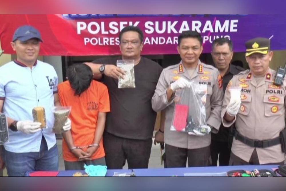 Suspek (dua dari kiri) kini ditahan polis yang turut ditemui dadah bersamanya. Agensi