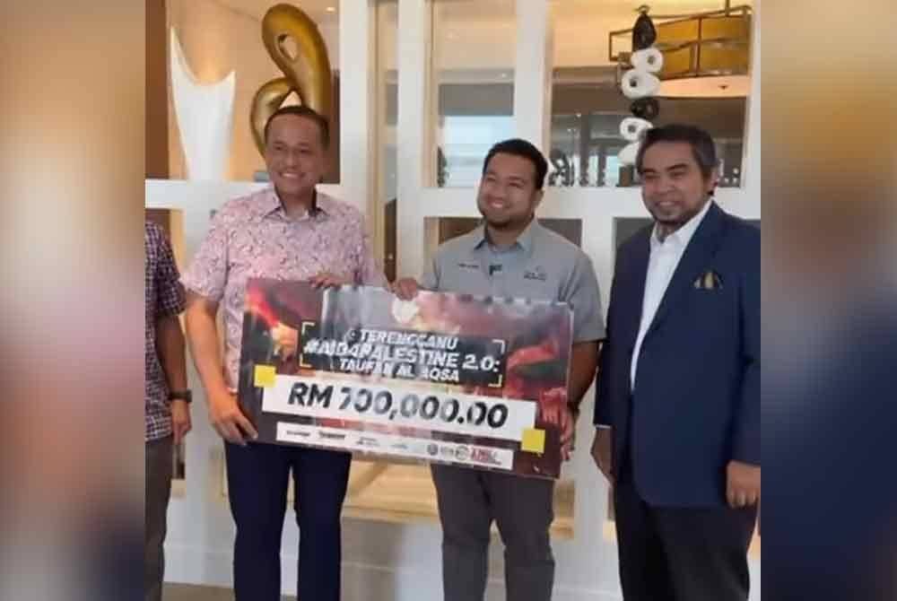 Ahmad Samsuri (kiri) menyerahkan replika cek bernilai RM700,000 kepada Muhammad Nadir Al-Nuri (tengah)