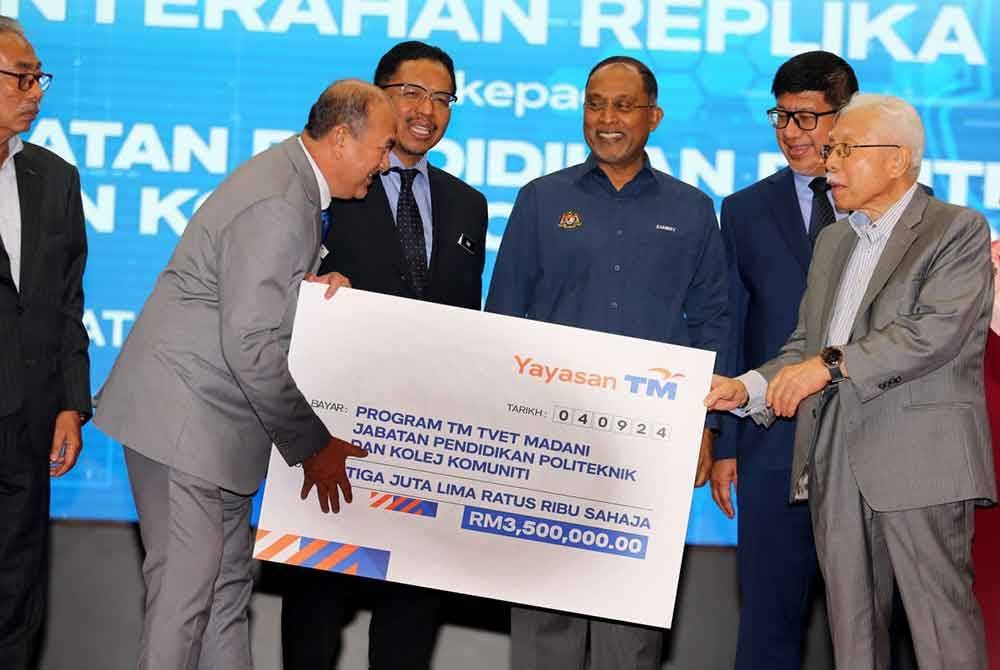 Zainal Abidin menyerahkan cek sumbangan berjumlah RM3.5 juta menerusi program TM TVET Madani@POLYCC kepada Mohd Zahari sambil diperhatikan Zambry (tiga dari kanan).