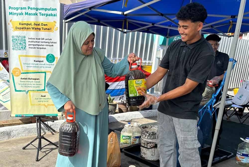 Norzila (kiri) membawa minyak masak terpakai untuk dijual.