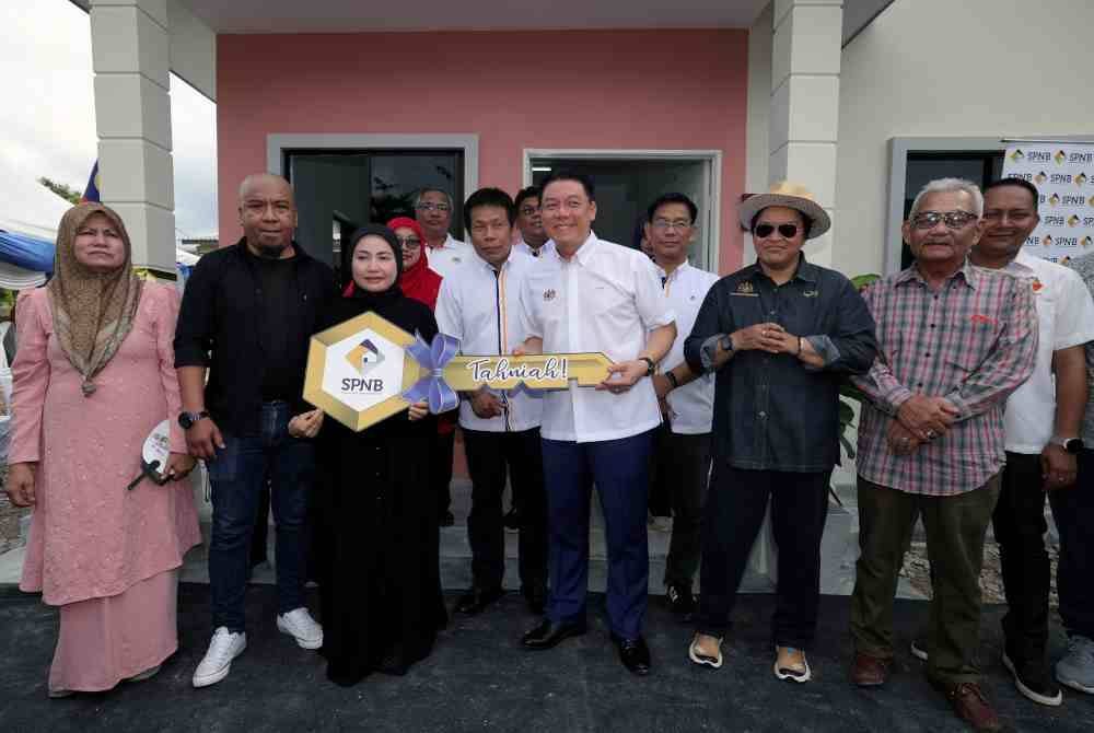 Menteri Perumahan dan Kerajaan Tempatan Nga Kor Ming (tengah) menyerahkan replika kunci rumah kepada pemilik Rumah Mesra Rakyat, Norhanisah Hasan, 34, (tiga, kiri) pada Program Sentuhan Kasih Kementerian Perumahan dan Kerajaan Tempatan di Felda Sungai Mas pada Jumaat. Foto Bernama