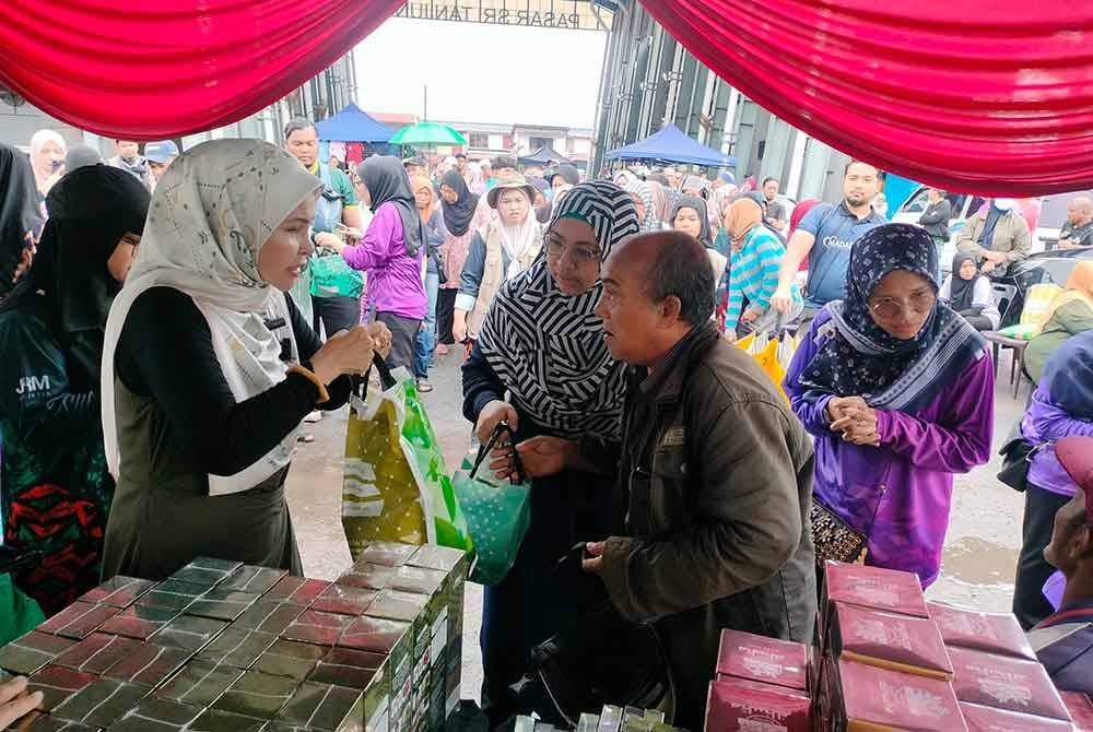 Rozita (kiri) menyampaikan sumbangan di Pasar Taman Sri Tanjung, Sungai Layar, Sungai Petani.