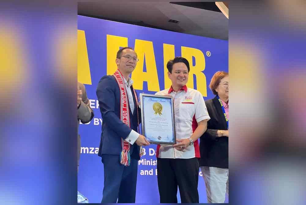 Nigel (kiri) menerima sijil daripada wakil Malaysia Book of Records selepas MATTA Fair diiktiraf sebagai &#039;Largest International Travel Fair&#039;.