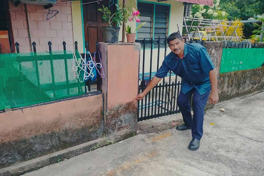 Mohamad menunjukkan paras air banjir yang pernah berlaku di Taman Ilham, Kluang.