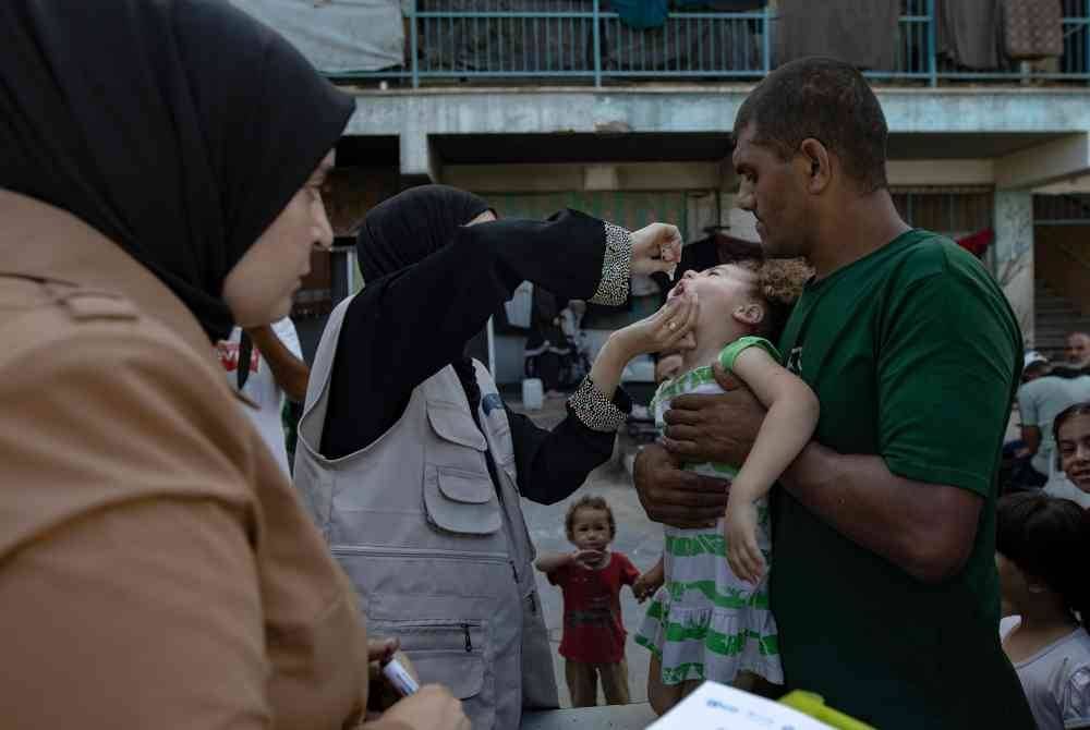 Seorang jururawat memberikan vaksin polio kepada kanak-kanak Palestin di sekolah PBB di kem Khan Yunis, selatan Semenanjung Gaza. Foto EPA