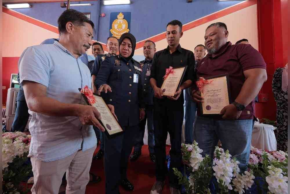 Wahiddin (kiri), Mohd Azwan (kanan) dan Qairulizwan menerima surat penghargaan hero bomba pada Perhimpunan Bulanan JBPM Perak di Balai Bomba dan Penyelamat Seri Iskandar pada Selasa.