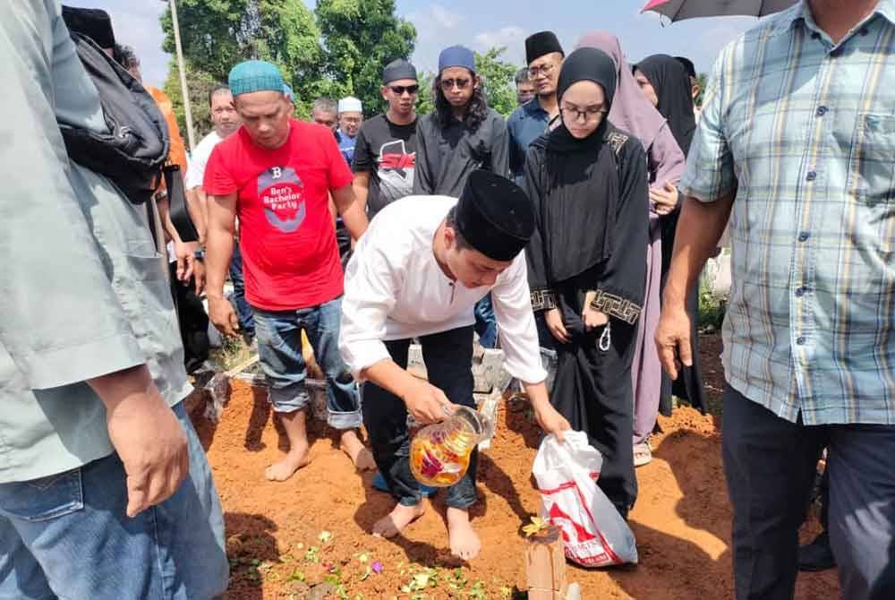 Syed Hussien menyiram air ke atas pusara ayahnya Syed Abdullah di Tanah Perkuburan Islam Kampung Melayu Kluang pada Rabu.