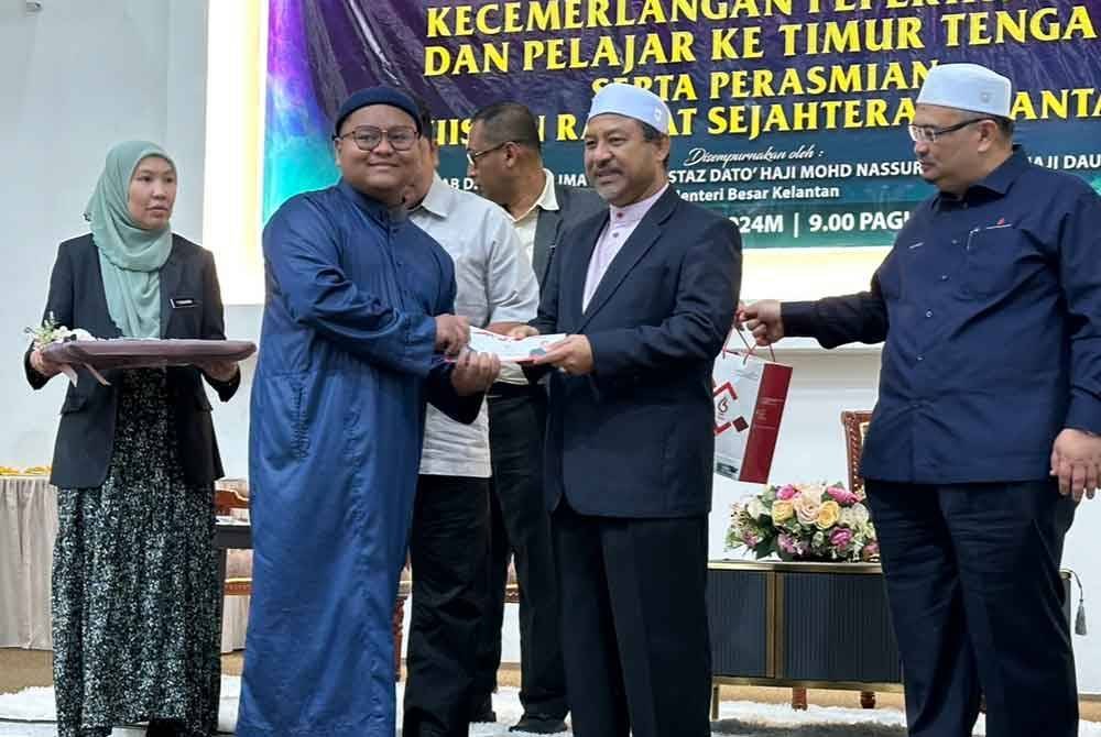 Pelajar menerima sumbangan dari Kerajaan Kelantan yang disampaikan Mohd Nassuruddin (dua dari kanan).