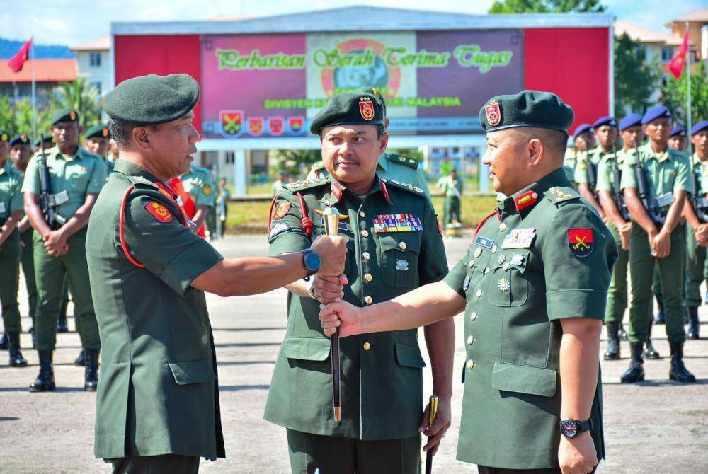 Malek (kiri) menyerahkan tongkat kuasa kepada Noorrul Azril (kanan) yang menjawat jawatan sebagai Panglima 5 Divisyen dan disaksikan Mohd Sofi (tengah) di Padang Kawad Rejimen Keenam Artileri Diraja (6 RAD), Kem Lok Kawi, Putatan.