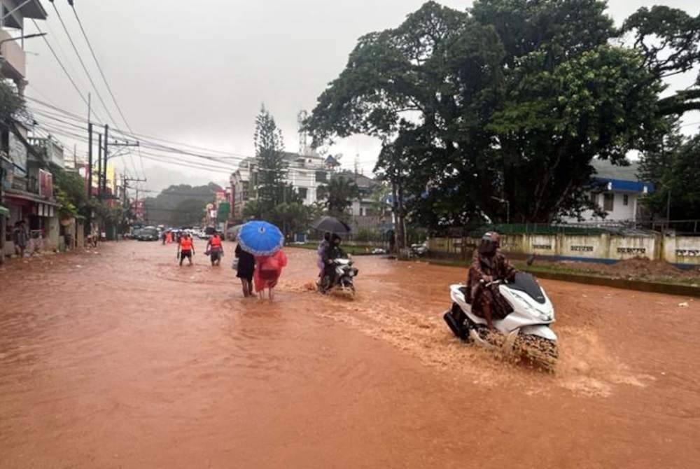 Orang ramai meredah air banjir di jalan di Tachileik di negeri Shan timur Myanmar, Selasa. Foto AFP-Yonhap