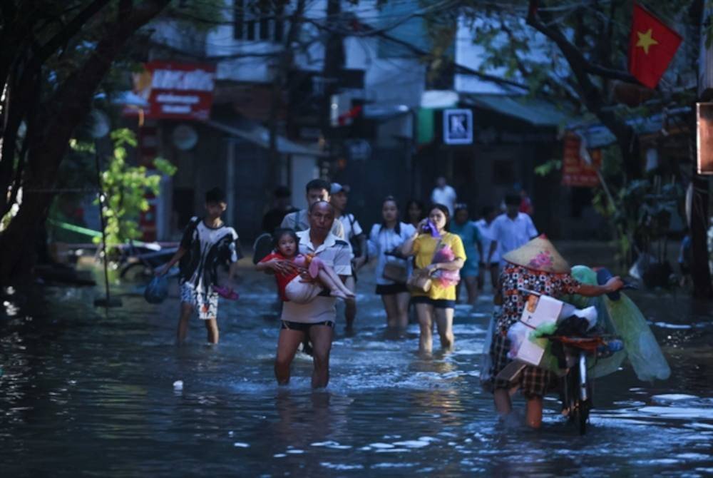 Penduduk terpaksa berpindah selepas rumah dinaiki air apabila paras air sungai di rantau tersebut meningkat ke tahap membimbangkan. Foto VNA/VNS