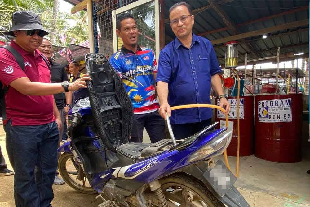 Azman membantu penduduk mengisi petrol semasa merasmikan Inisiatif Pendigitalan Sektor Peruncitan di Pasar Terapung dan Pelancaran Program Penyeragaman Harga Zon Tumpat di Pulau Sri Tanjong, Tumpat pada Sabtu.