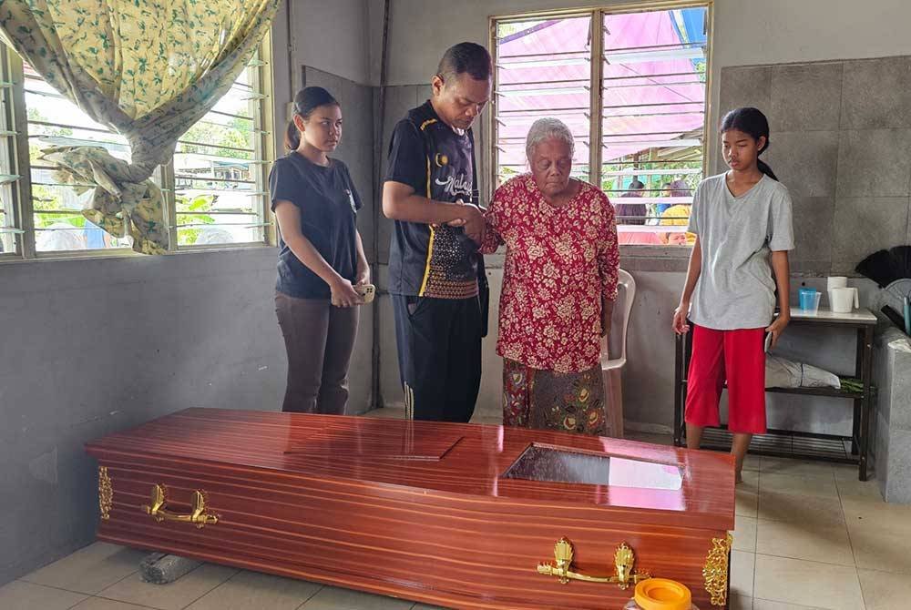 Mulyadi memimpin tangan ibunya, Krig untuk melihat wajah mendiang Apot buat kali terakhir di kediamannya di Kampung Batu Berangkai, Kampar.